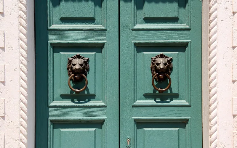 ornate cast door knocker hardware set into a carved wood door panel ornate cast door knocker hardware set into a carved wood door panel