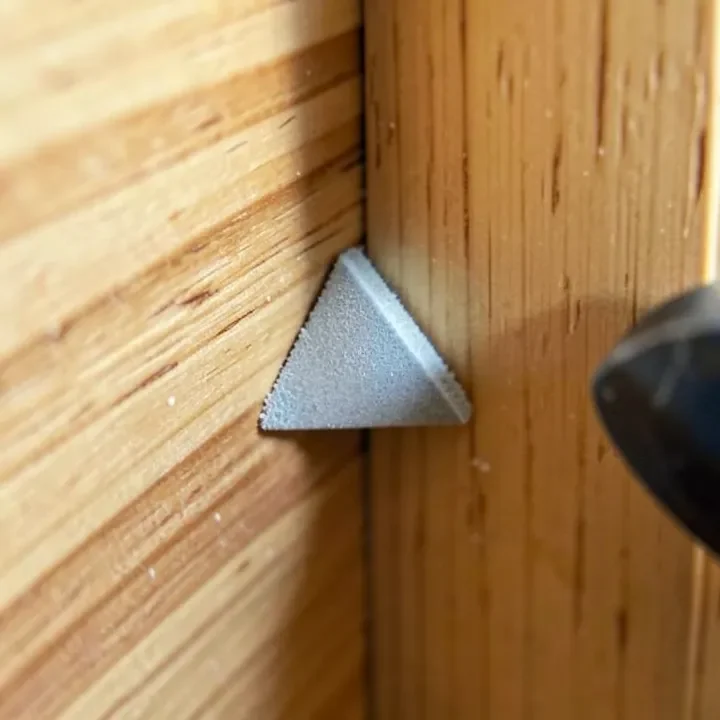 Small triangular detail sander sanding into a wood corner