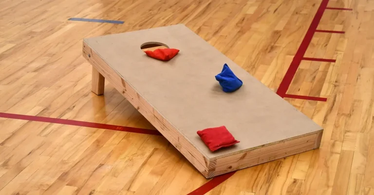 finished wooden cornhole board with a hole cut in the top and red and blue bean bags resting on the playing surface