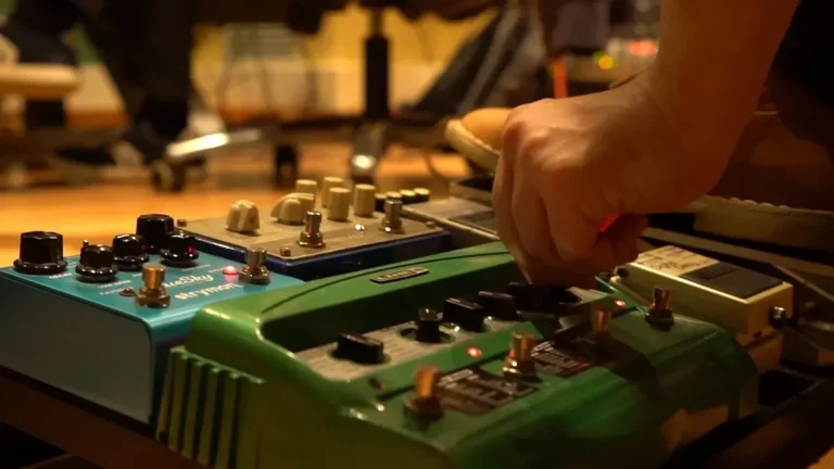 Guitarist adjusting a row of effects pedals mounted on a pedalboard