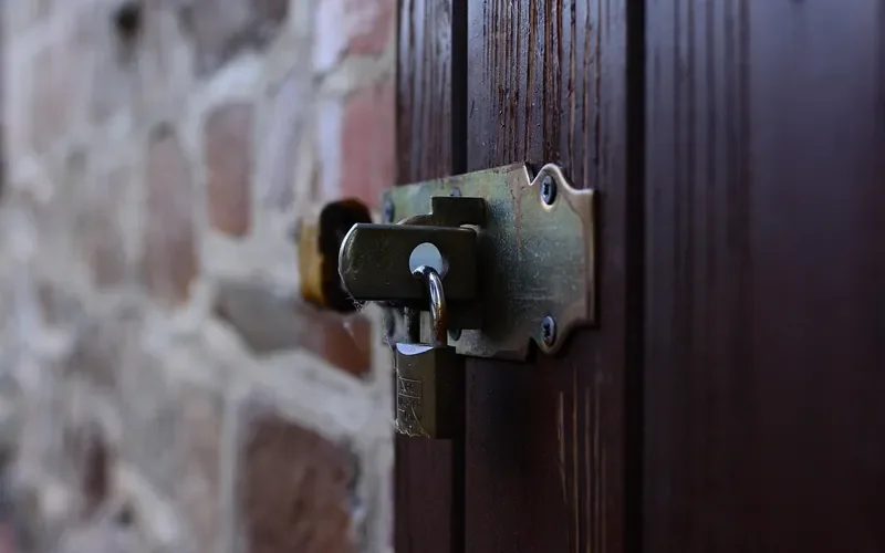 Metal latch hardware screwed onto a dark wooden door Metal latch hardware screwed onto a dark wooden door