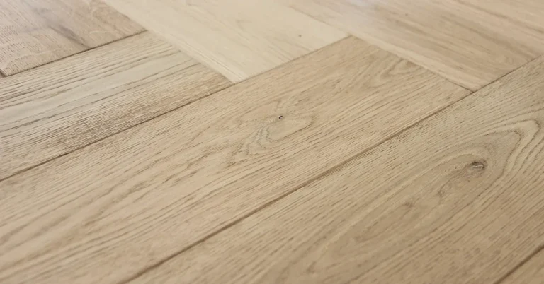 Herringbone teak-style wood floor close-up showing warm golden grain and tight parquet joints