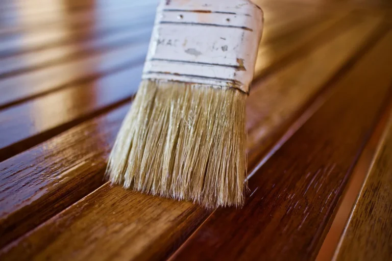 Applying tung oil or wood finish with a brush on wooden surface