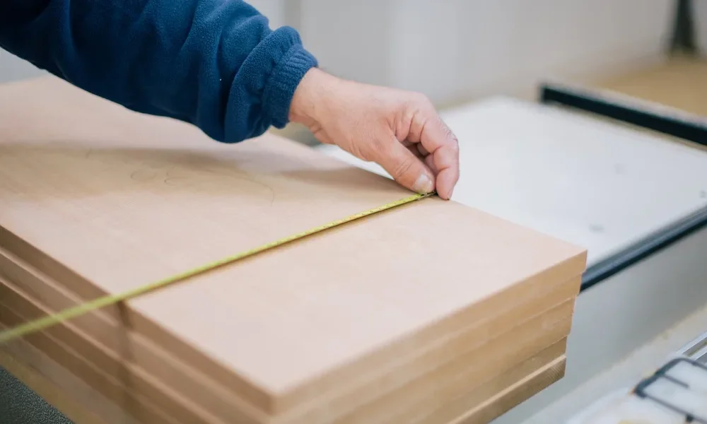 Tape measure laid across a stack of plywood panels before cutting drawer dividers