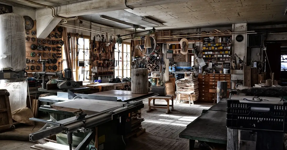 Woodworking shop with table saw, workbenches and hand tools hung on the wall