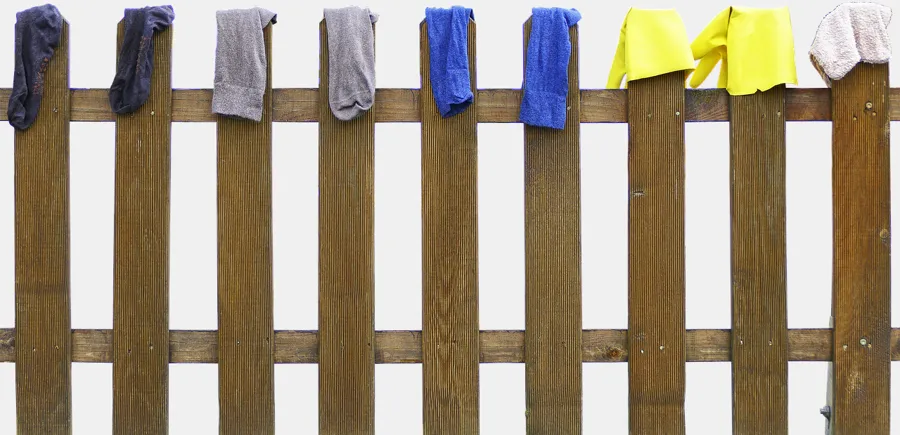 Work rags and gloves spread over a wooden fence to dry in open air Work rags and gloves spread over a wooden fence to dry in open air