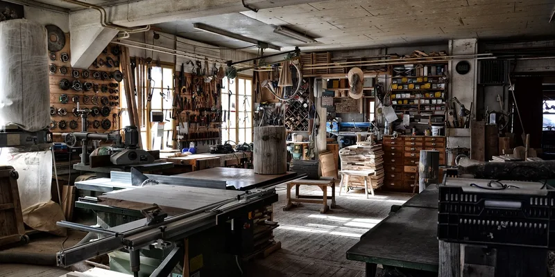 organized woodworking workshop with wall-mounted hand tools and a table saw