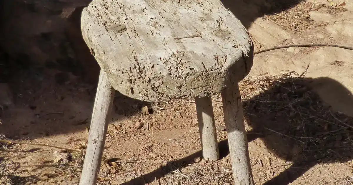 Rustic wooden stool with splayed legs standing on the ground