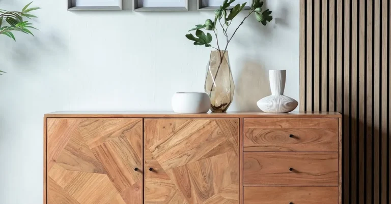 Light wood sideboard with plants and abstract art against a white wall