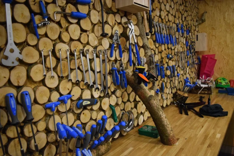 Wrenches, pliers, and hand tools organized on a wall rack in a workshop