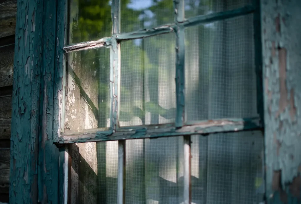 Weathered wooden window frame with peeling paint before glazing repair