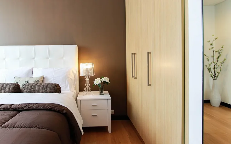 modern bedroom with wood wardrobe and hardwood floor beside an upholstered bed