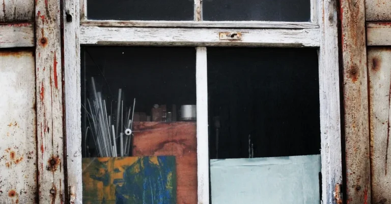 Weathered wooden window frame with peeling paint, the kind of exterior trim where wood rot starts