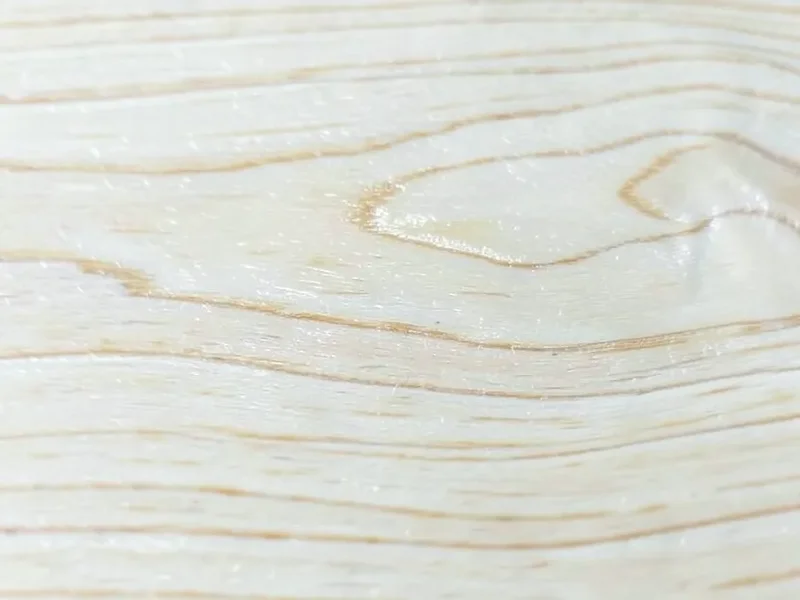 Close-up of pale birch wood grain with fine wavy lines and silky texture