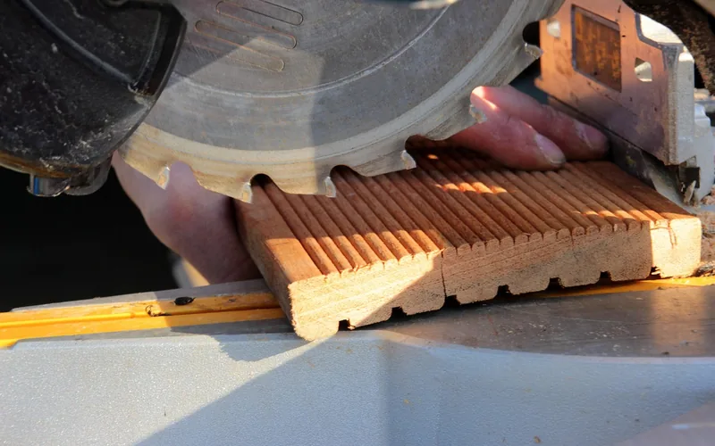chop-style miter saw with blade guard raised over a wooden board before a crosscut