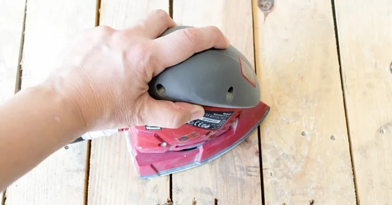 Hand sanding an MDF furniture surface with a power sander before applying wood filler