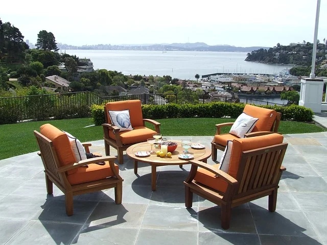 Teak outdoor patio furniture set with cushions on a stone terrace