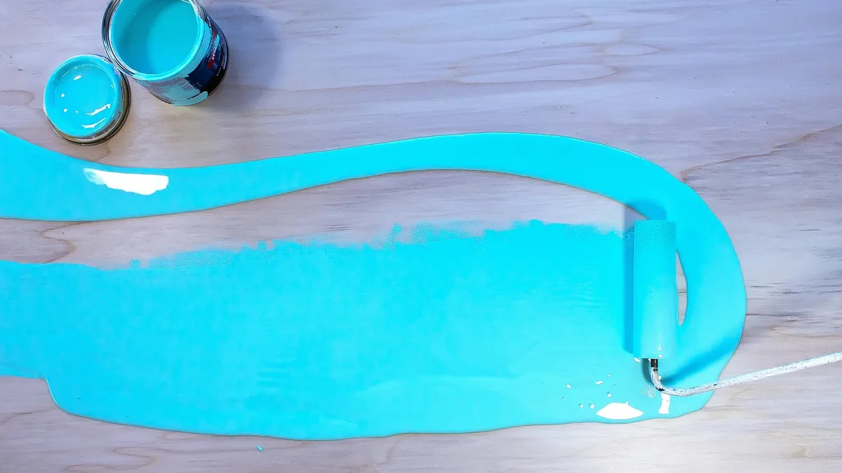 Open paint can and roller with teal paint for choosing an MDF furniture paint color