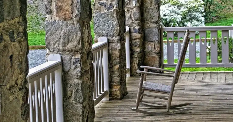 Wooden porch floor with a rocking chair between stone pillars