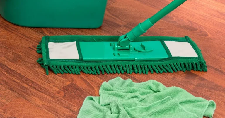 Microfiber flat mop resting on a sealed hardwood floor next to a folded cloth