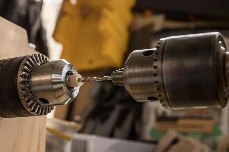 Drill chucks with a bit and a wood dowel in a workshop Drill chucks with a bit and a wood dowel in a workshop