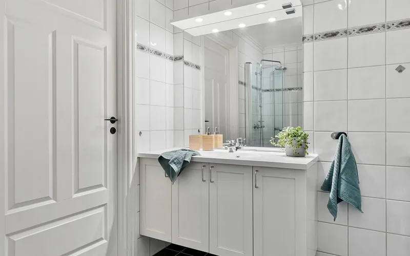 white bathroom vanity cabinet near a sink and shower where moisture collects
