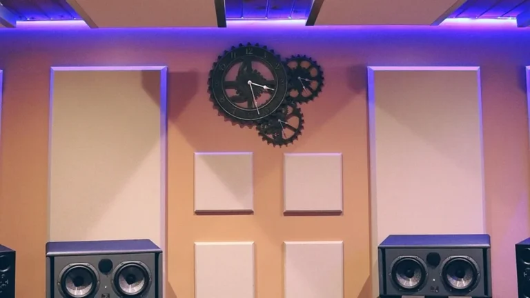 Home recording studio wall with absorber panels behind studio monitor speakers