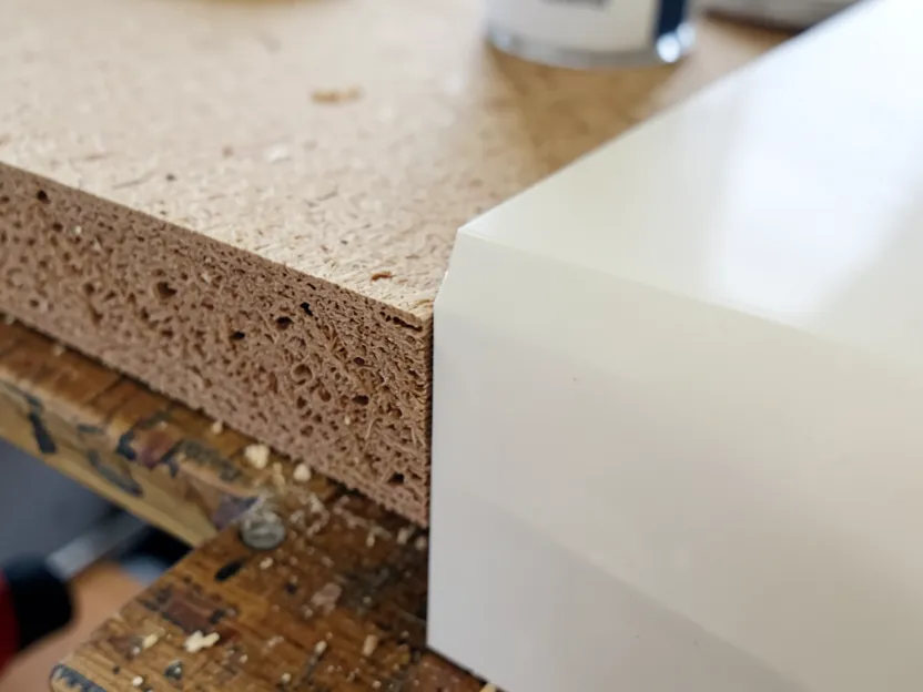 Raw MDF edge showing its dense fibrous core next to a smooth primed and finished surface