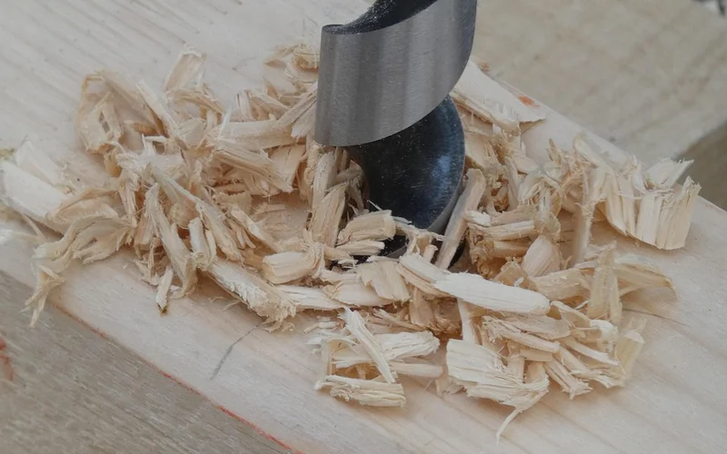 Drilling a fresh pilot hole into wood with visible wood chips