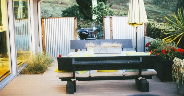 small wooden deck in a compact backyard garden with bench seating and string lights