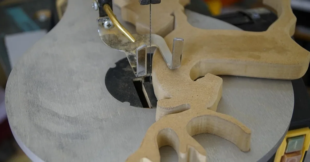 scroll saw cutting a wooden deer-shaped cutout with the blade in the table slot