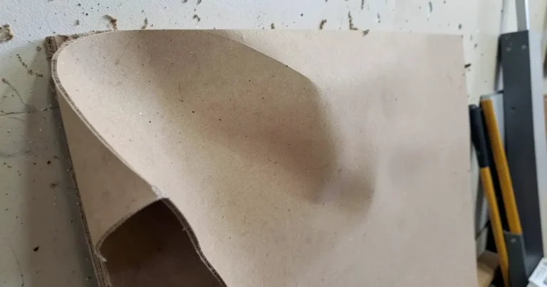 A sheet of MDF board visibly bowed and warped at the edge