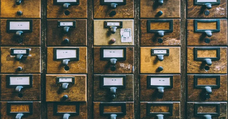Rows of aged wooden card-catalog drawers with a darkened, worn finish
