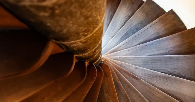 Close view of wooden stair treads fanning around a central column