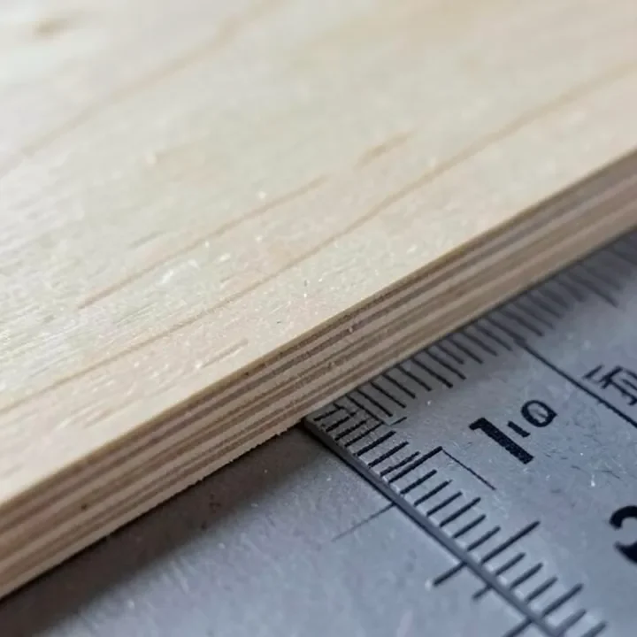 Close-up of thin plywood edge layers with a ruler for scale