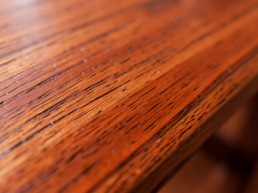 Close-up of the grain and reddish-brown color of finished cherry wood furniture