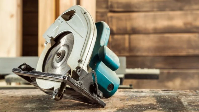 Close-up of a cordless circular saw blade and shoe resting on a workbench