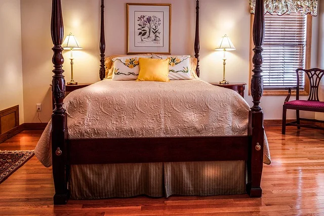 Bedroom with dark wood flooring styled with warm bedding and decor