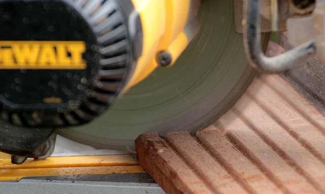 DeWalt 12-inch double bevel miter saw cutting a board, close-up of the blade and motor housing
