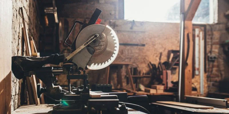DeWalt battery-powered miter saw set up in a home workshop with sunlight through the window
