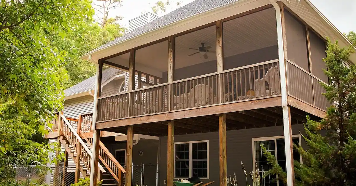 Elevated pressure-treated wood deck with covered porch and stairs on a two-story home