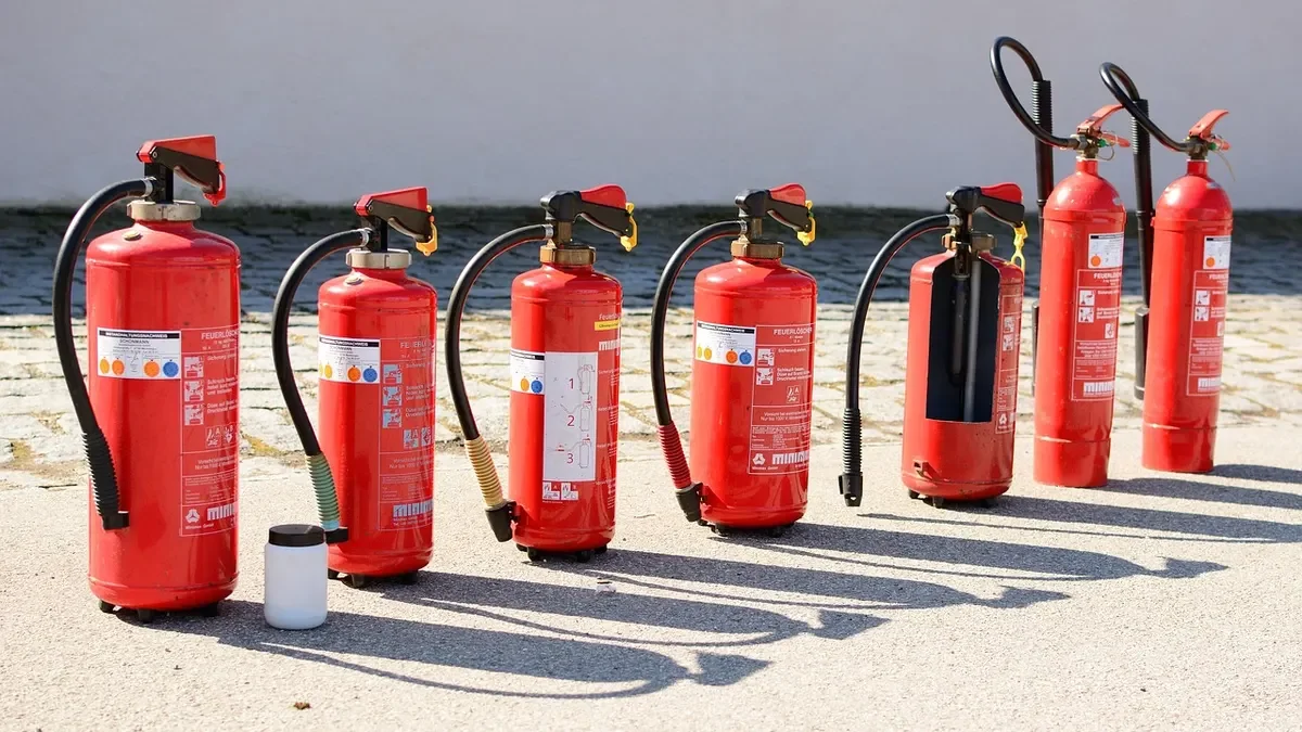 Row of red portable fire extinguishers standing on pavement