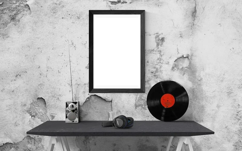 Black framed print hanging on a weathered painted concrete wall above a desk