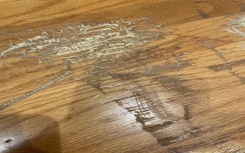 Cleaning supplies laid out next to a scuffed hardwood floor