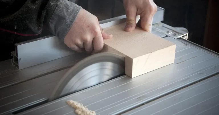 Hands guiding a wood board through a saw blade during a straight cut