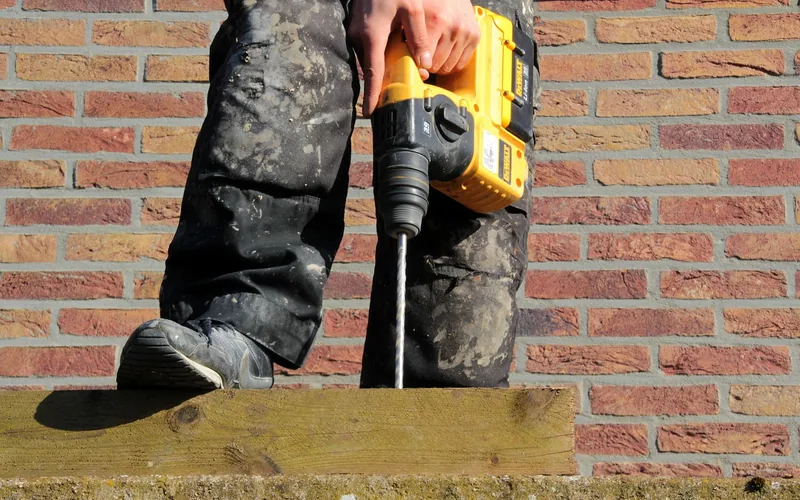 cordless impact drill boring a mounting hole into a concrete wall cordless impact drill boring a mounting hole into a concrete wall