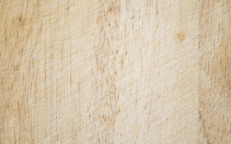Close-up of a used wooden cutting board surface covered in fine knife marks