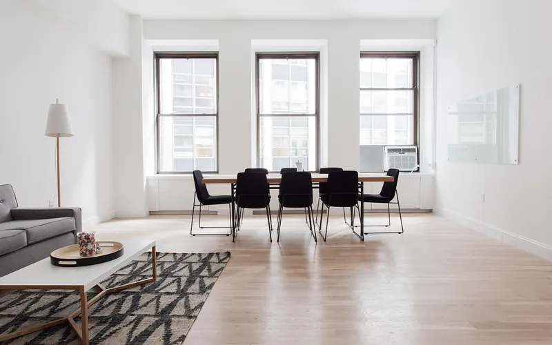 Open room with a light hardwood floor, a rug and a sofa