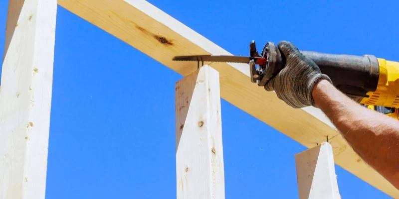 A reciprocating saw cutting through a wood framing brace