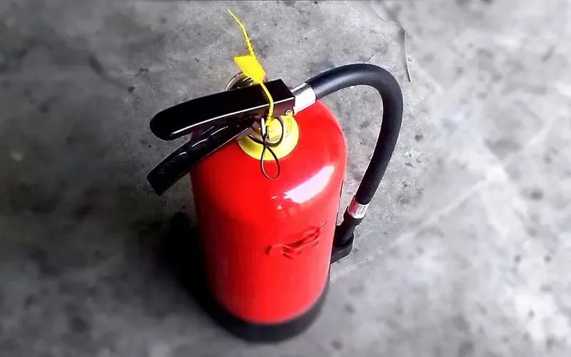 Red portable fire extinguisher with the safety pin tag in place